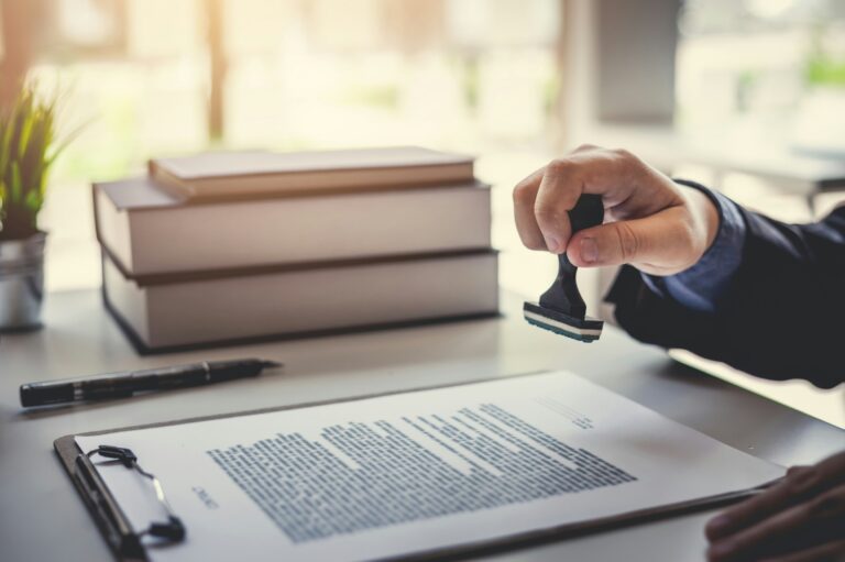 A hand holding a stamp above a document on a clipboard
