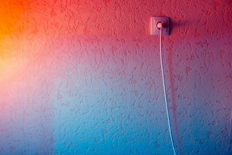 A white cable plugged into a white wall socket