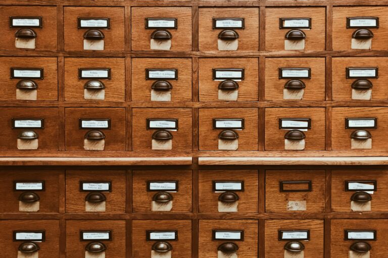 An open wooden card catalog drawer full of index cards
