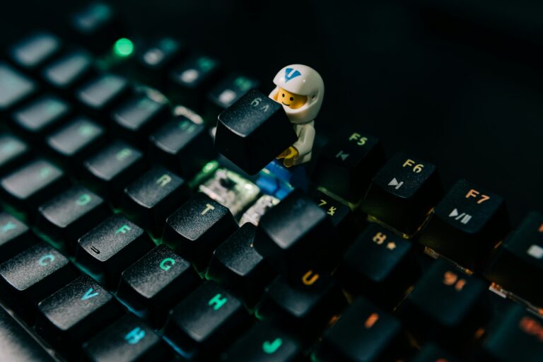 A small toy figure lifting a key on a dark keyboard