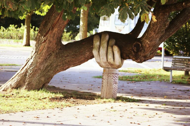 A carved wooden hand supporting a heavy tree branch