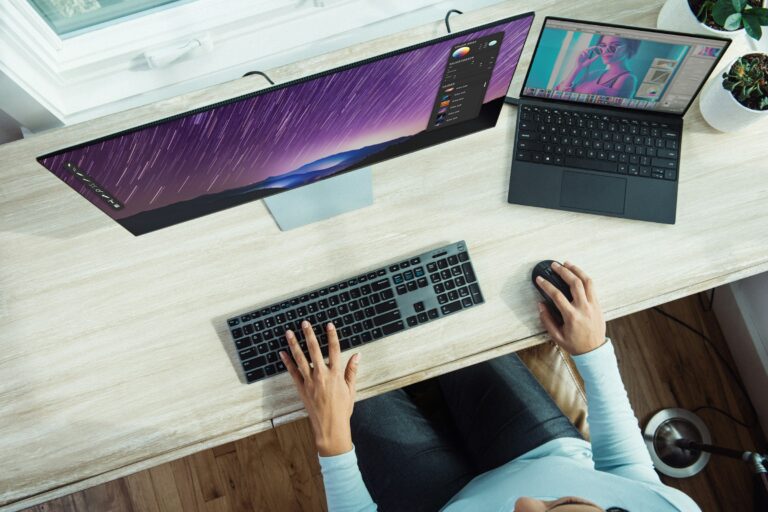 A person working at a desk with a laptop and a large monitor