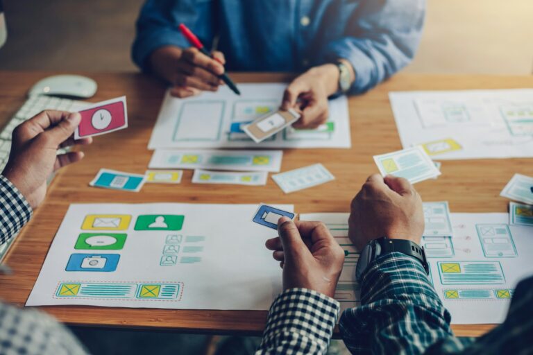 A team arranging paper wireframe cards on a table