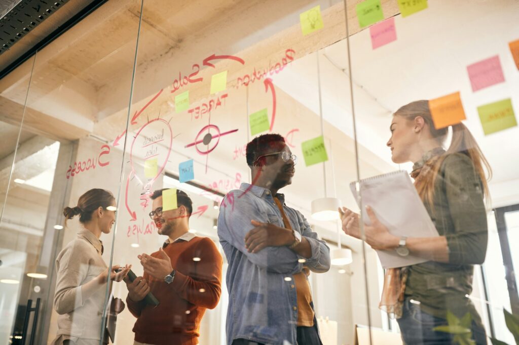 A team discussing ideas in front of a glass wall covered in notes