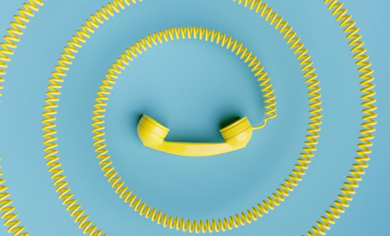 A yellow telephone handset with a coiled cord on a blue background