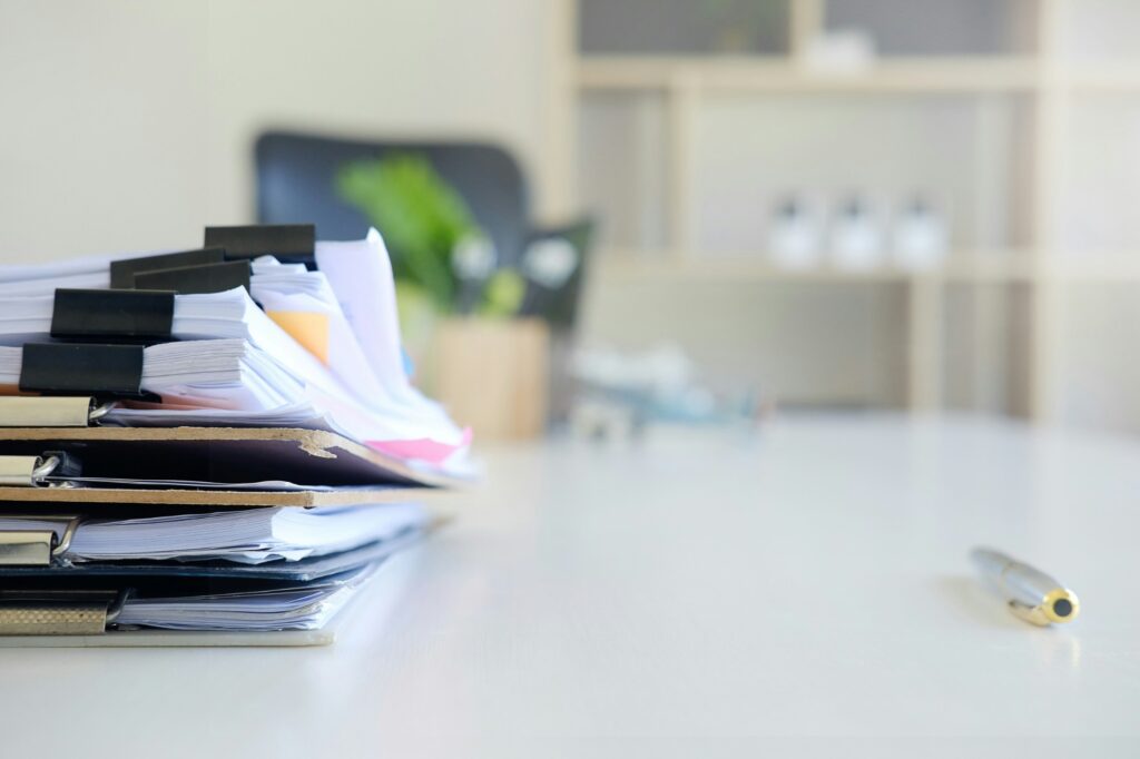 A stack of clipped case files and a pen on an office desk