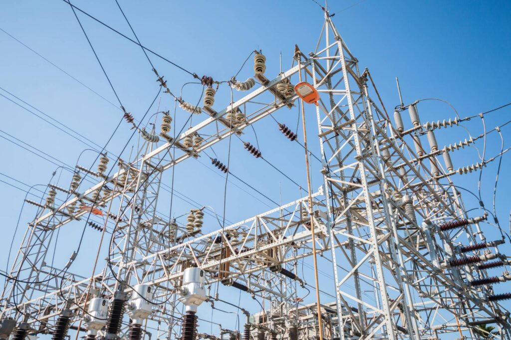 Steel towers and power lines at an electrical substation against a blue sky